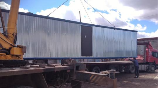 погрузка манипулятором подержанного блок-контейнера для перемещения на другой объект